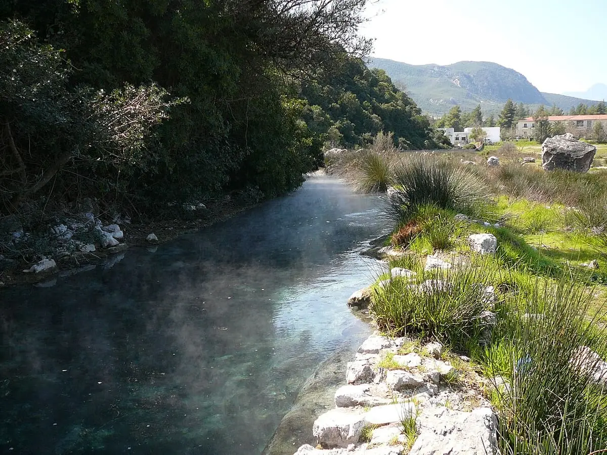Steaming hot stream flowing between grassy banks toward the hills at Thermopylae