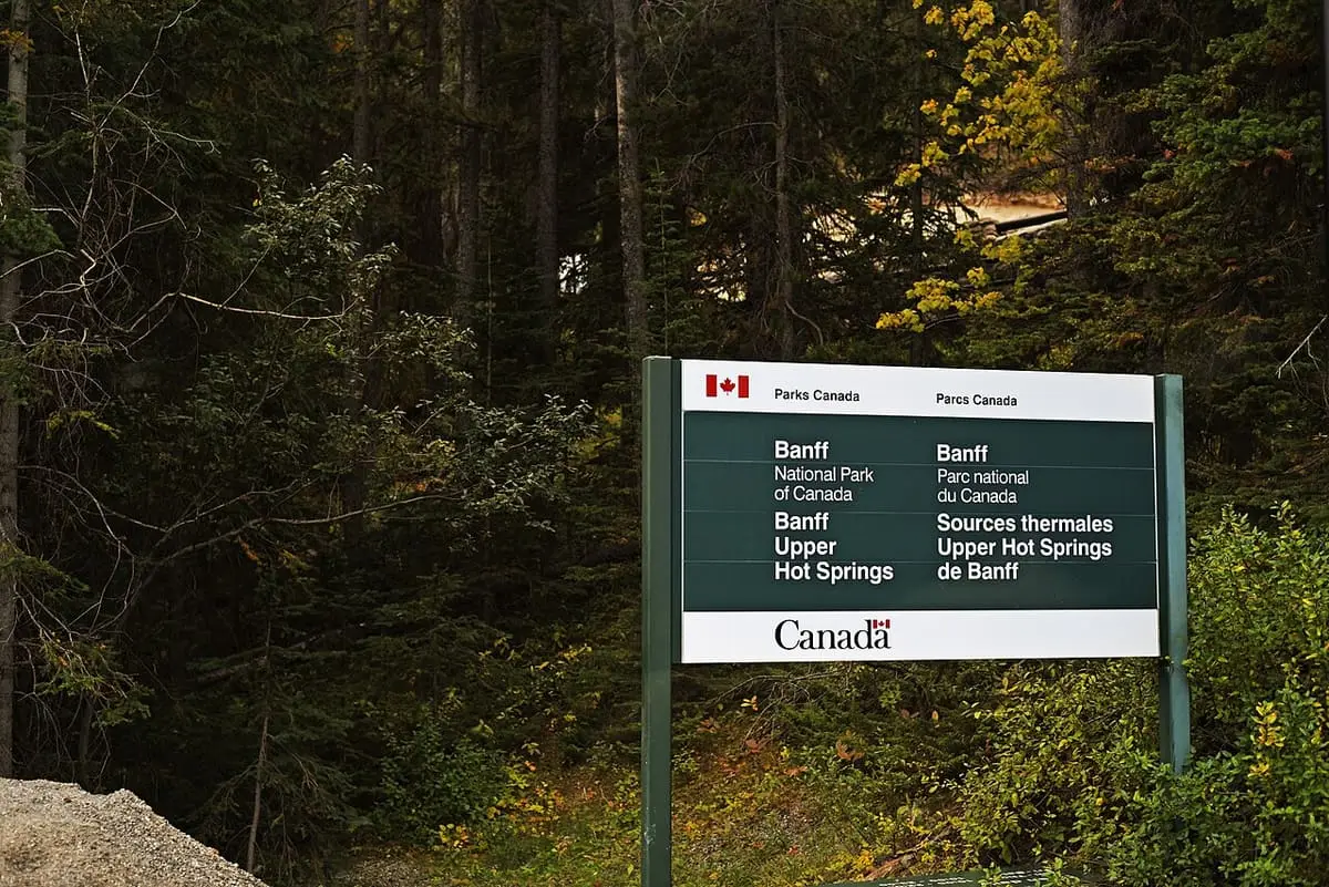 Parks Canada sign for Banff Upper Hot Springs among dark evergreen trees