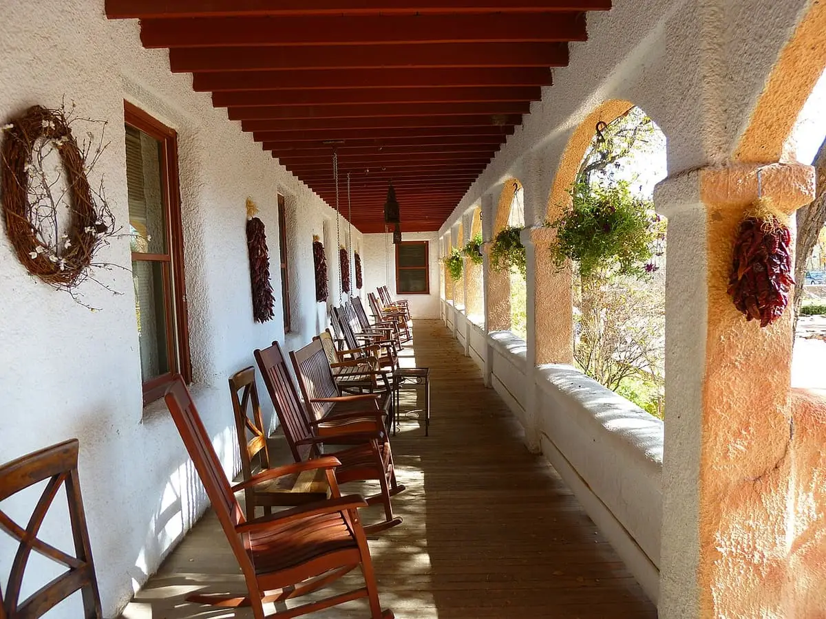 Long covered portal with wooden chairs, wreath and chile ristras at Ojo Caliente Mineral Springs