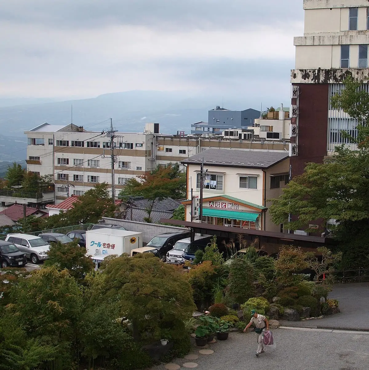 View over Ikaho Onsen rooftops and gardens toward distant hills from a hillside inn