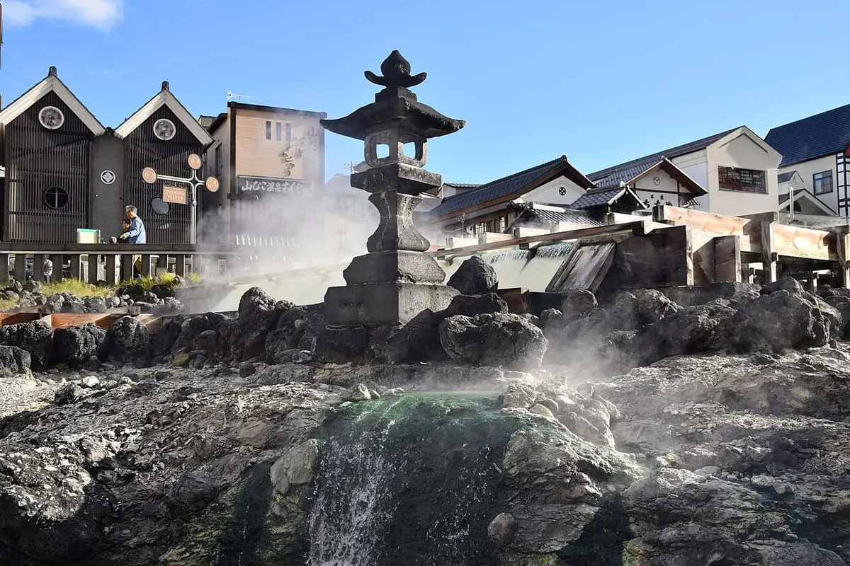 Steam rising from volcanic rocks and a stone lantern at the Yubatake in Kusatsu Onsen