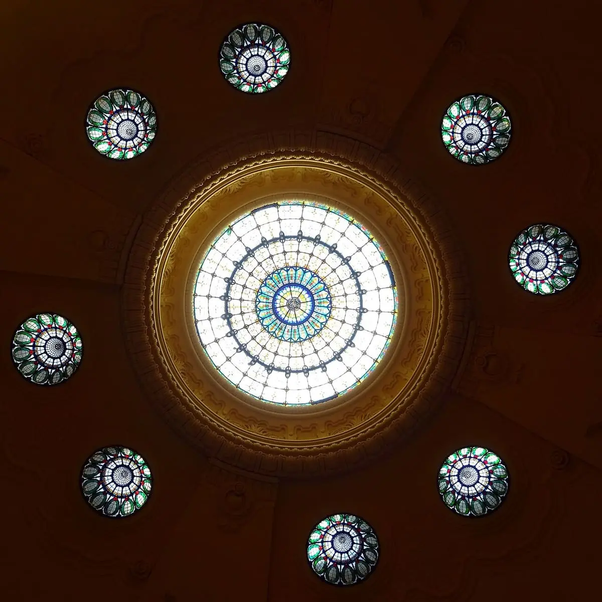 Stained glass skylights set in the dark dome ceiling of the Gellért Bath