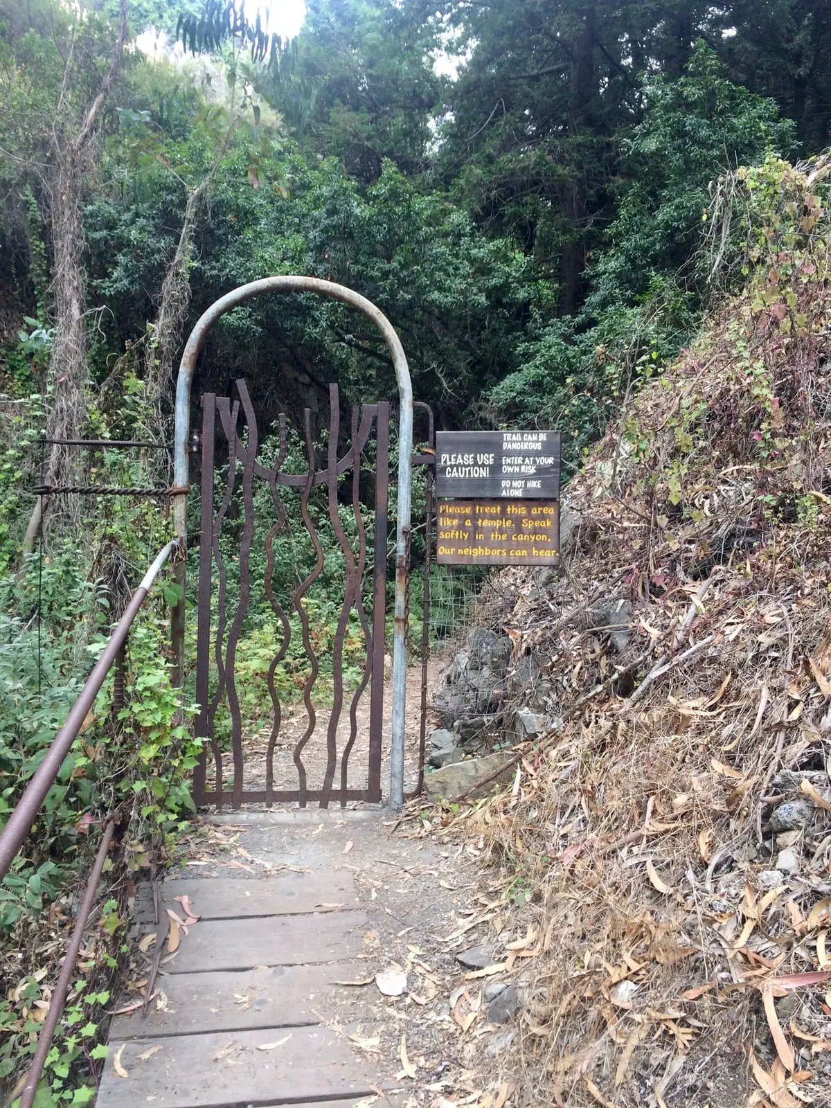 Wooden gate and trail sign at the start of a hiking trail at Esalen Institute