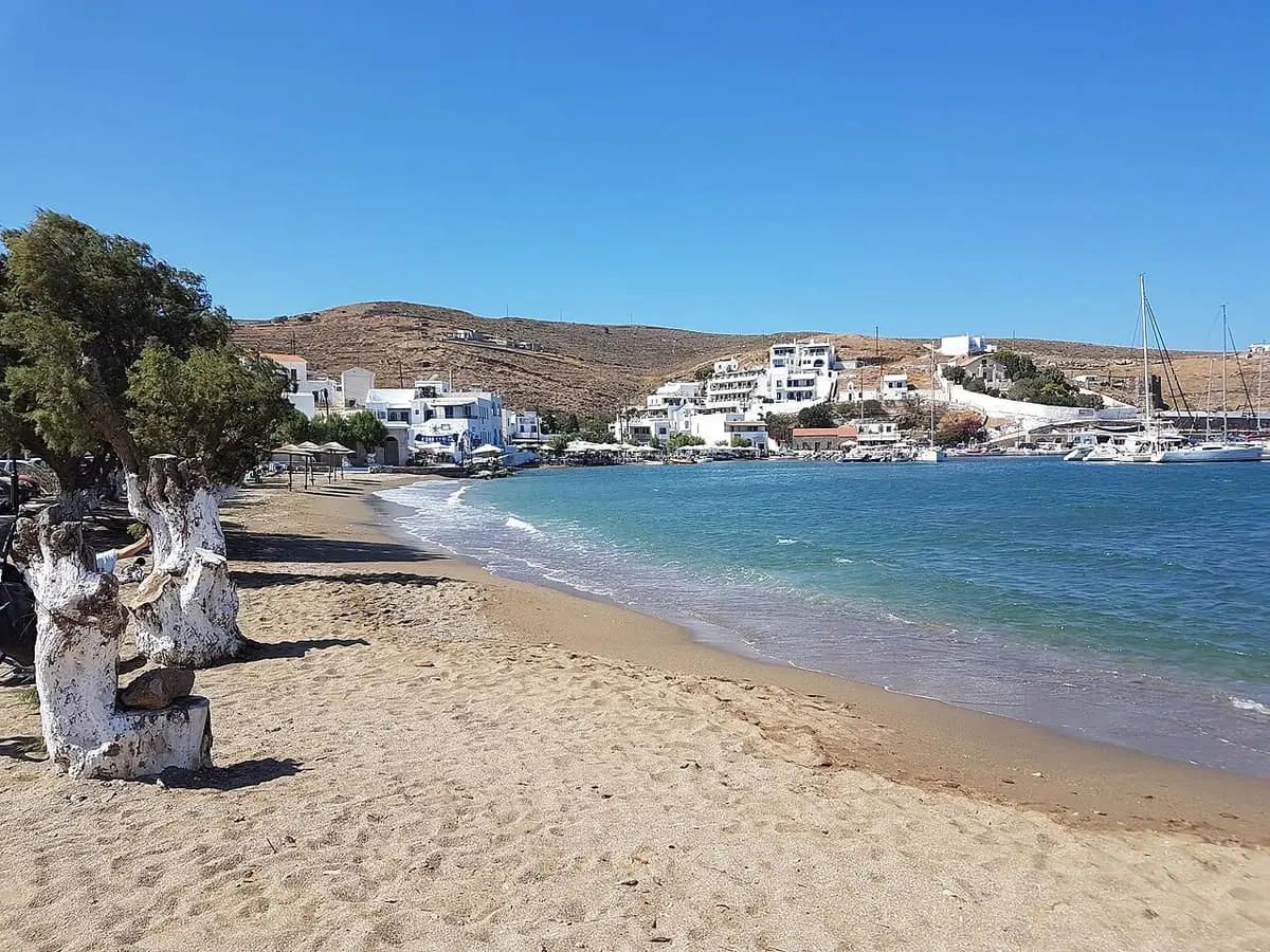 Sandy beach curving along Loutra bay on Kythnos with village houses and hills beyond