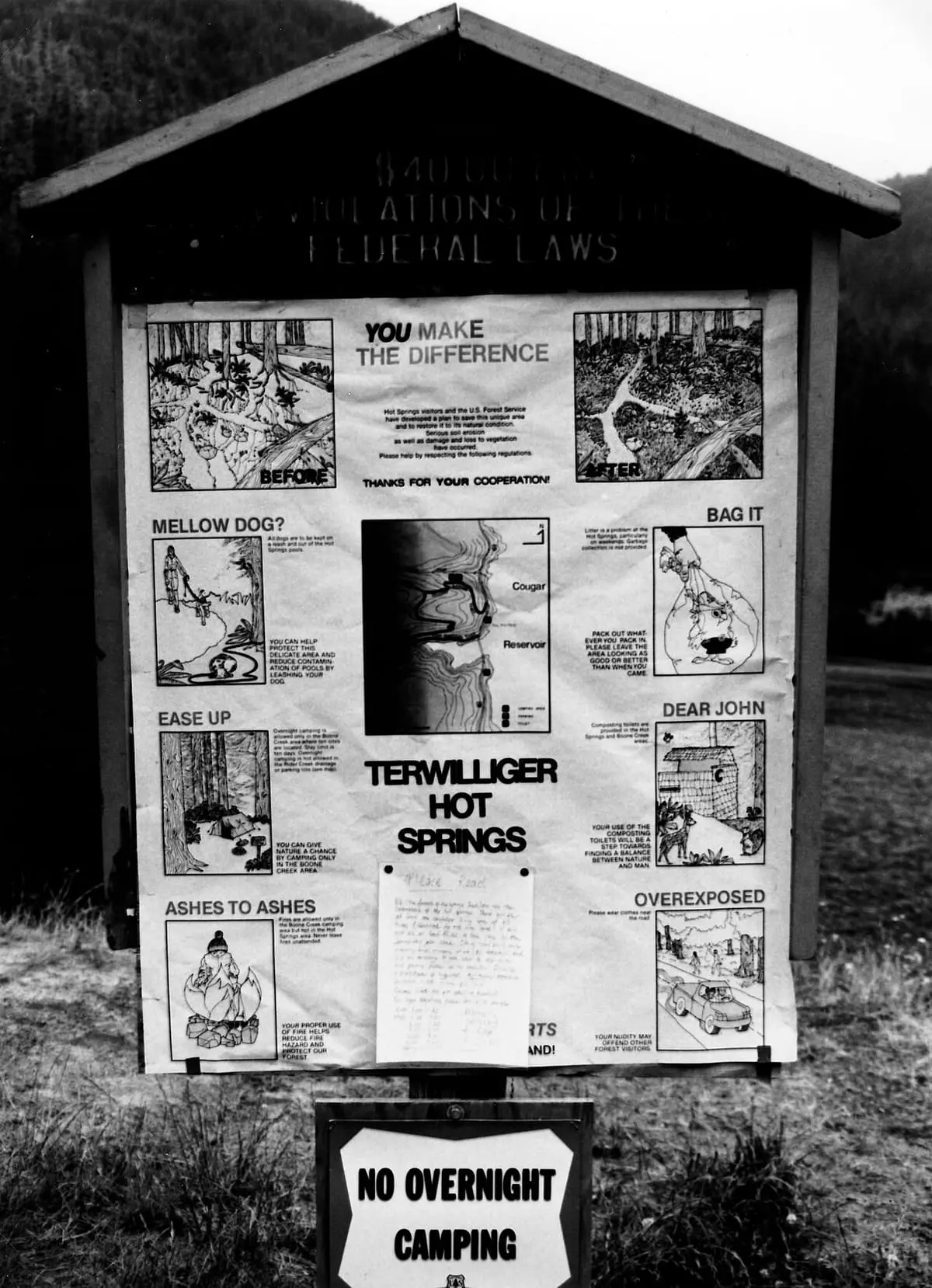 Black and white trailhead bulletin board for Terwilliger Hot Springs with a no overnight camping sign