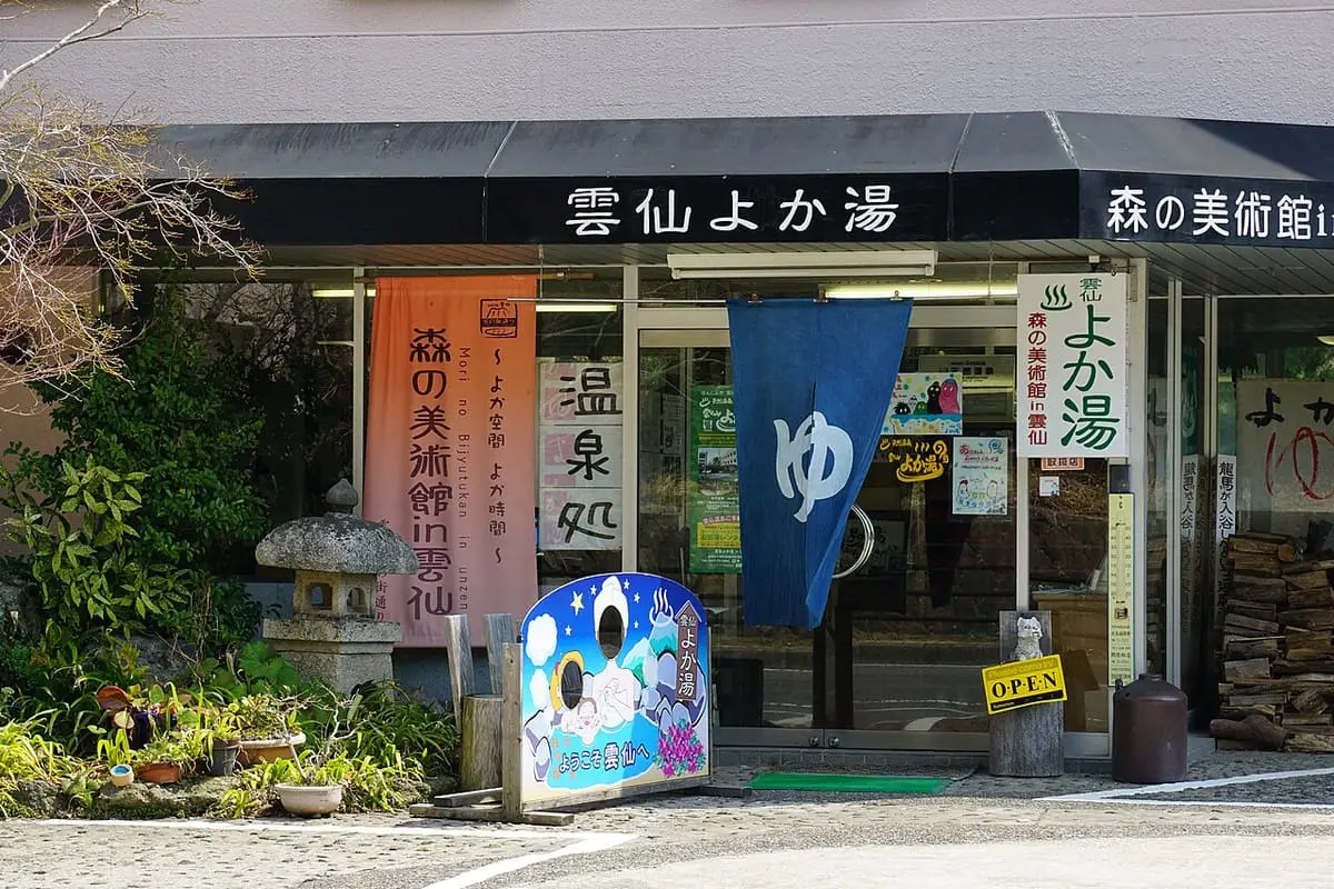Entrance of the Unzen Yokayu public bath with a blue yu curtain and signs