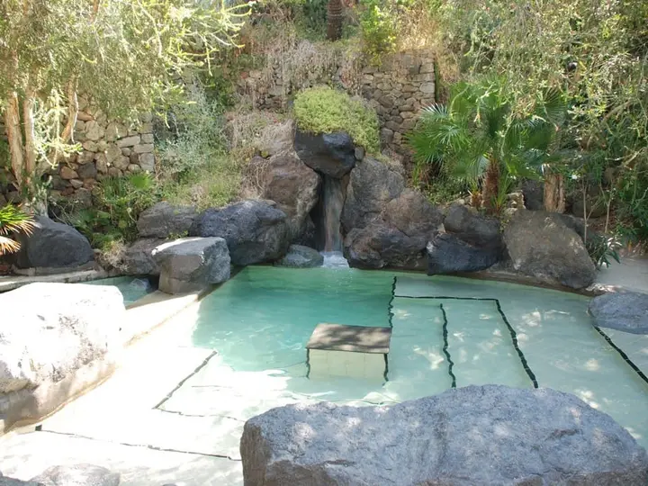 Rock edged Maya thermal pool with a small waterfall in the gardens of Parco Termale Negombo