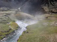 Steam rising from the warm Reykjadalur river as it winds through a green valley
