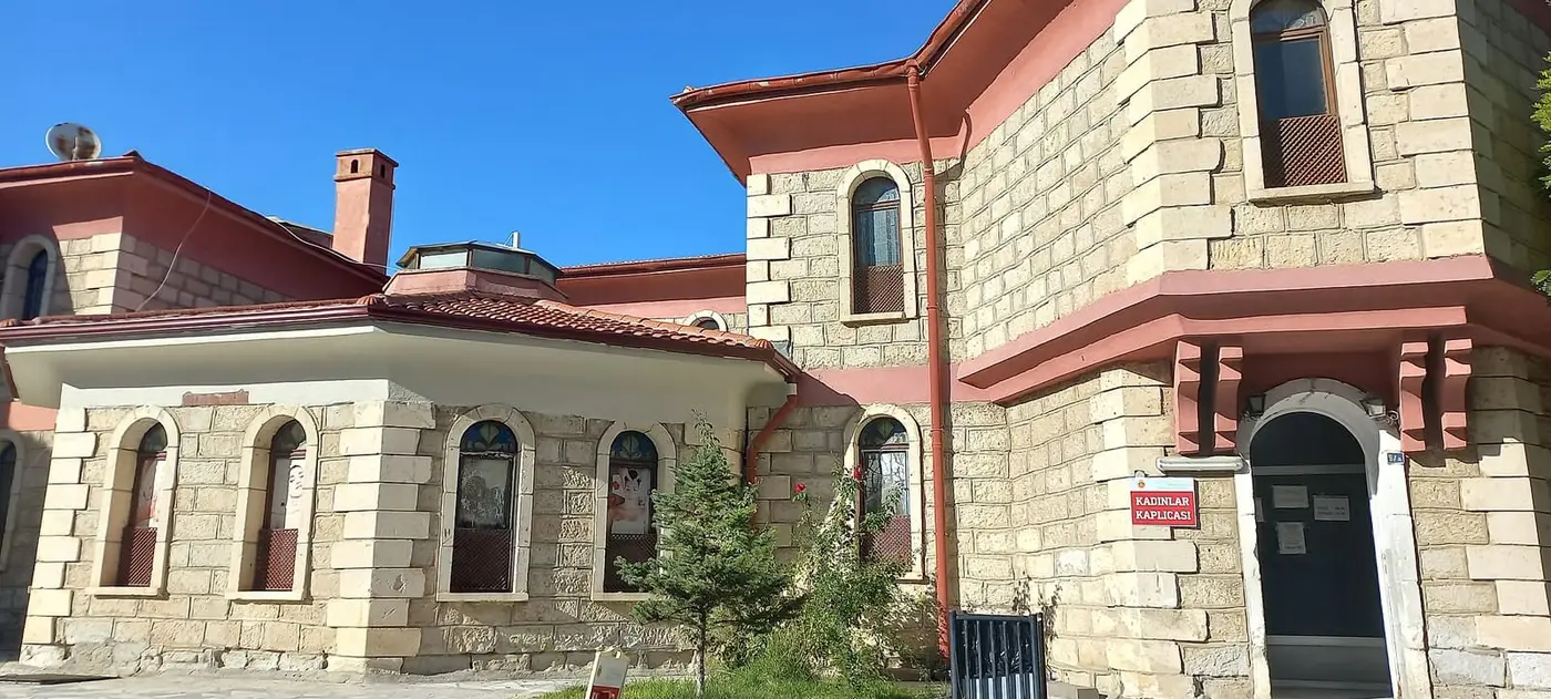 Stone and red trimmed Gazlıgöl thermal bath building with a women's bath entrance sign