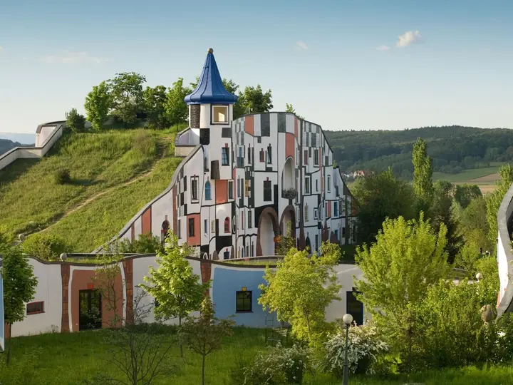 Colorful Hundertwasser Kunsthaus building with grass roof and golden spire at Rogner Bad Blumau