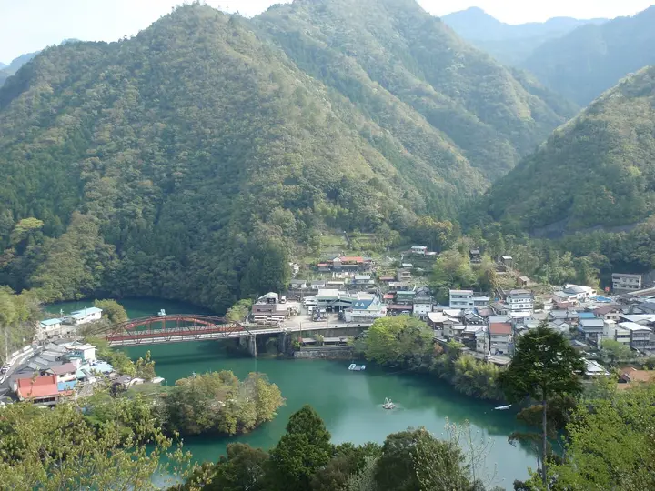Totsukawa Onsen town beside the green waters of Lake Futsuno, surrounded by forested mountains
