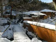 Snowy wooden walkway leading to the Sainokawara Rotenburo bath buildings in Kusatsu