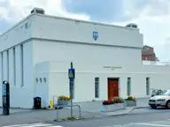 White 1937 Sundhöll Reykjavíkur building with tall columns and a red entrance door