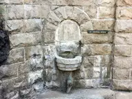 Arched stone fountain niche with a spout and a Dripping Spring nameplate in an old stone wall
