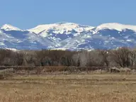 Snowy San Juan Mountains and Bennett Peak seen west across flat pastureland from Highway 17 near Alamosa