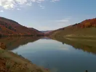Calm reservoir water reflecting autumn hillsides in the valley near Maple Grove Hot Springs