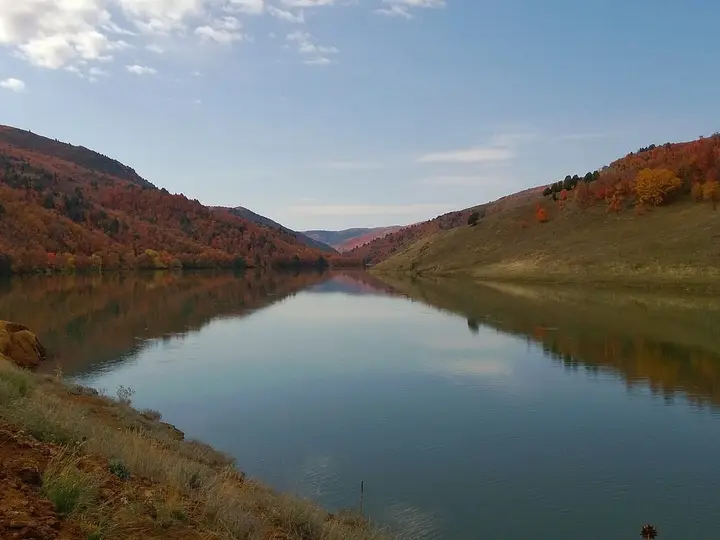 Calm reservoir water reflecting autumn hillsides in the valley near Maple Grove Hot Springs
