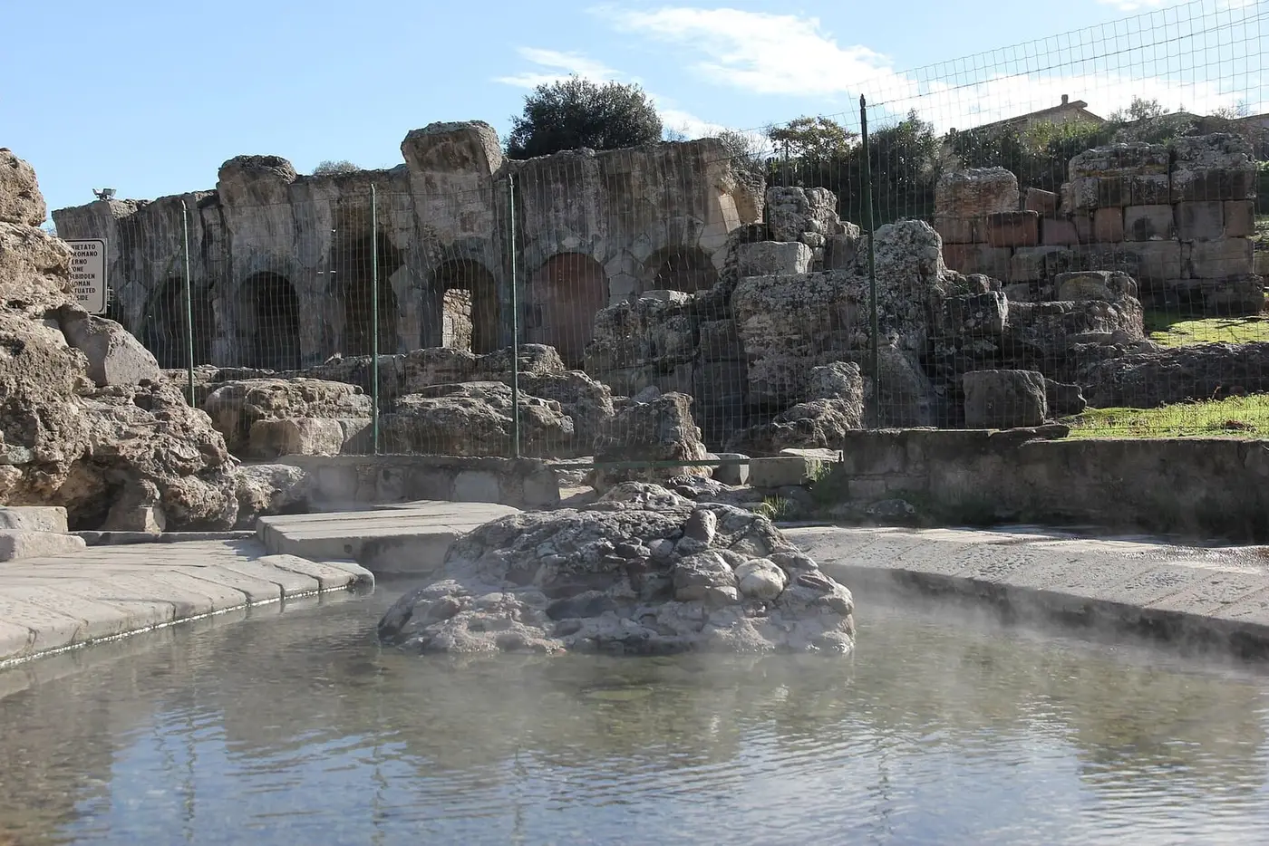 Steaming hot spring pool beside the ruined Roman bath arches at Fordongianus
