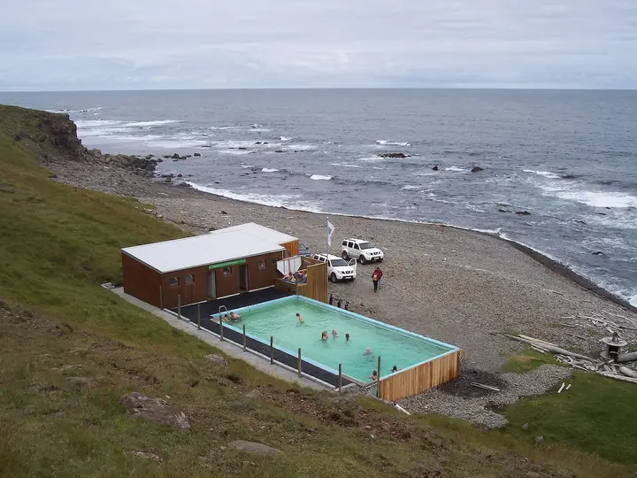 Krossneslaug outdoor pool and wooden changing hut on a pebble beach beside the open sea