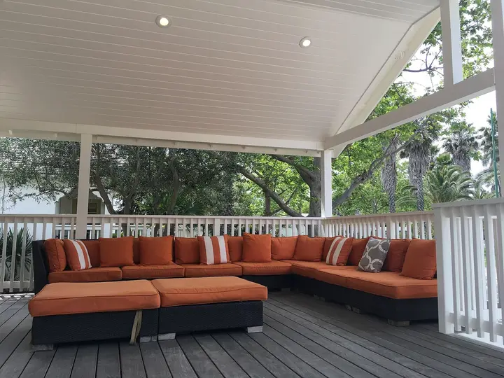 Covered lounge deck with orange sofas among trees at Indian Springs Resort in Calistoga