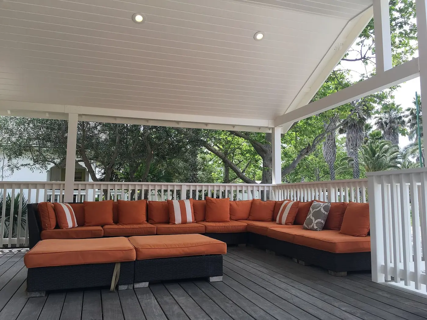 Covered lounge deck with orange sofas among trees at Indian Springs Resort in Calistoga