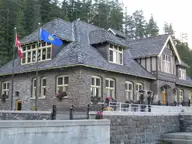 Stone Upper Hot Springs bathhouse in Banff with flags and pine forest behind