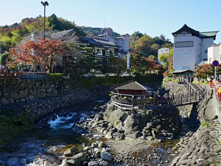 Shuzenji River flowing over rocks past the Tokko no Yu pavilion and onsen town buildings