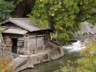 Wooden riverside bathhouse beside the rushing Tanohara River at Kurokawa Onsen in autumn