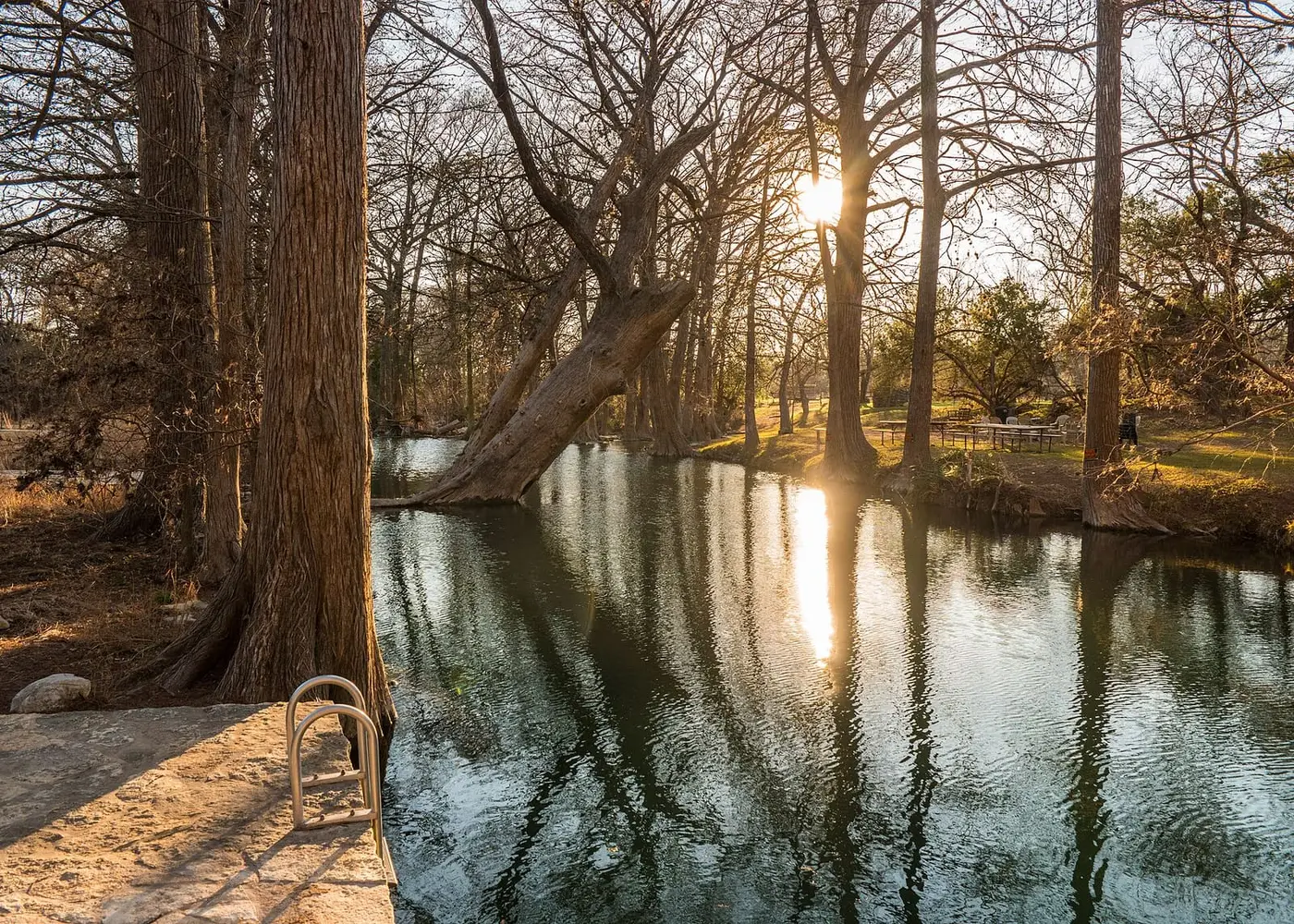 Cypress Creek swimming hole at Blue Hole Regional Park with tall cypress trees and low sun