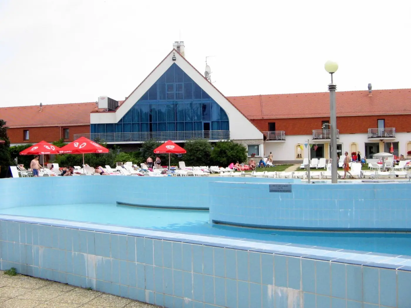 Outdoor pool in front of the glass gabled main building of Kehida Termál