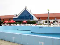 Outdoor pool in front of the glass gabled main building of Kehida Termál