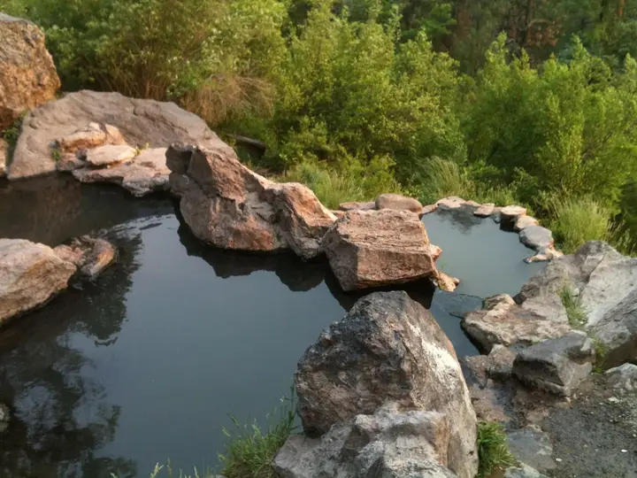 Rock rimmed upper and lower pools of Spence Hot Spring surrounded by green brush