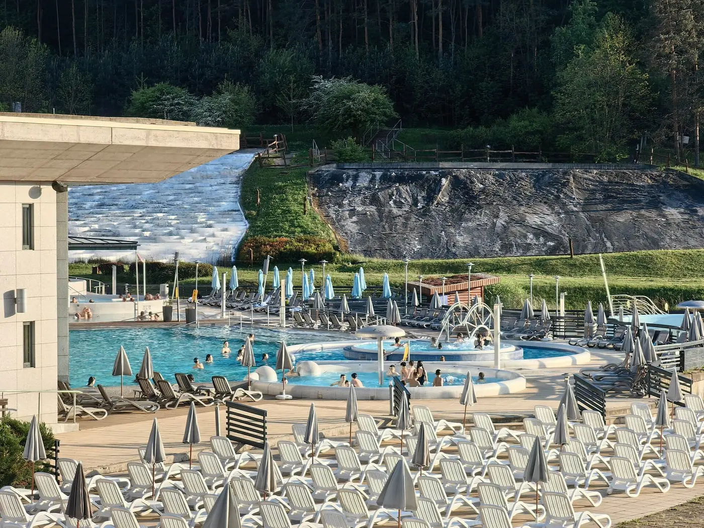 Outdoor thermal pools and sun loungers at Saliris Resort with the white travertine hill behind
