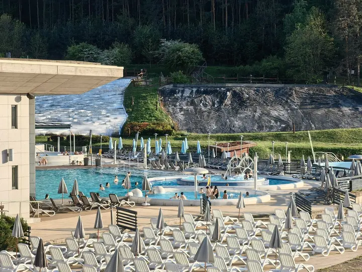 Outdoor thermal pools and sun loungers at Saliris Resort with the white travertine hill behind