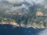 Aerial view of the Esalen Institute grounds on the Big Sur coastline under low evening clouds