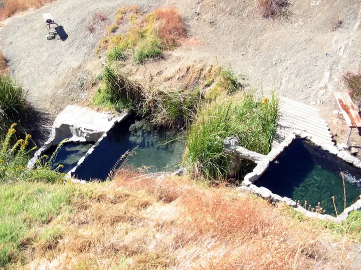 Two small concrete rimmed soaking pools at Little Caliente Hot Springs on a dry grassy hillside
