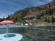 Large outdoor hot springs pool with a mushroom fountain below the red cliffs of Ouray