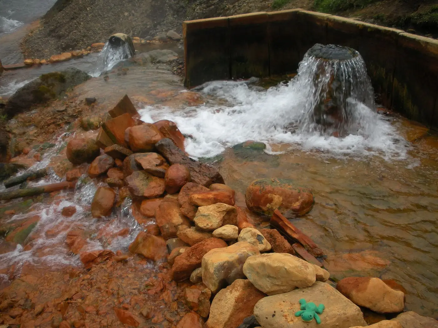 Hot water pouring into a wood walled thermal pool over orange stained rocks at Kerlingarfjöll