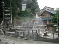 Steaming Okama hot spring pools surrounded by stone walls and railings in Nozawa Onsen