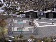 Two concrete soaking pools inside wooden rail fences beside changing rooms at Sharkey Hot Springs
