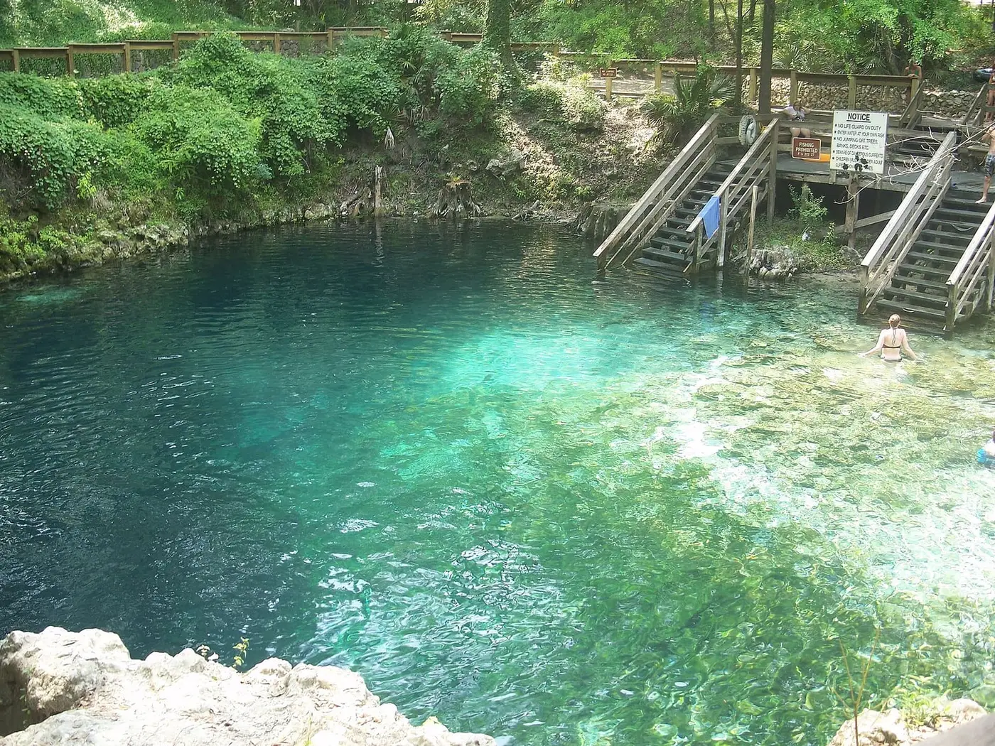 Turquoise Madison Blue Spring basin below limestone banks and wooden swimmer stairs
