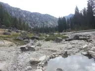 Rock lined soaking pool at Sacajawea Hot Springs below forested mountains along the South Fork Payette