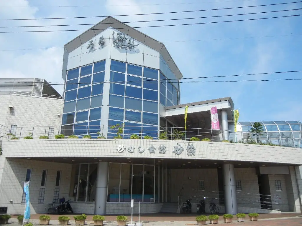 Glass tower entrance of the Sunamushi Kaikan Saraku sand bath hall at Ibusuki Onsen under blue sky
