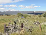 Sagebrush meadow and old wooden fence at Fales Hot Springs with grazing cattle and distant mountains