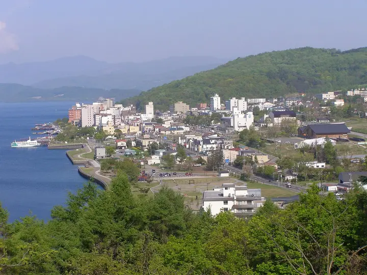 Toyako Onsen town spread along the shore of Lake Toya below green hills
