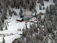 Silver Creek Plunge in winter, its steaming pool among snowy cabins and fir forest
