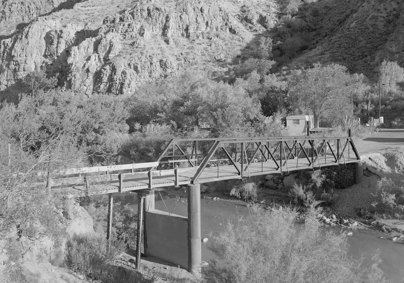 Black and white view of the old Hurricane LaVerkin truss bridge over the Virgin River in its rocky gorge