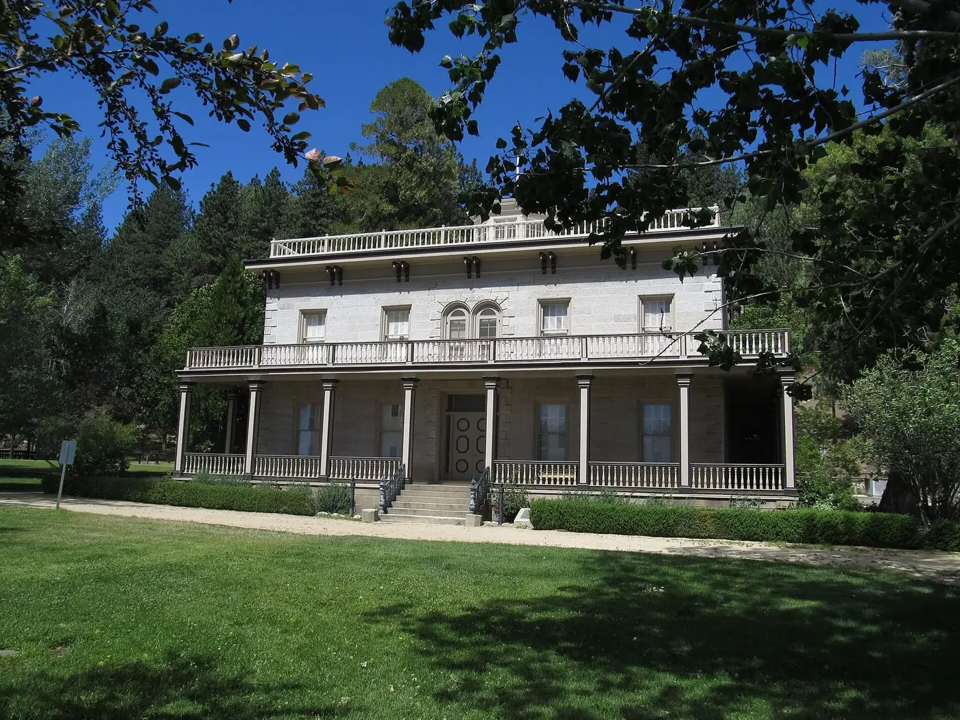 Front of the historic two story Bowers Mansion with wide verandas behind a green lawn