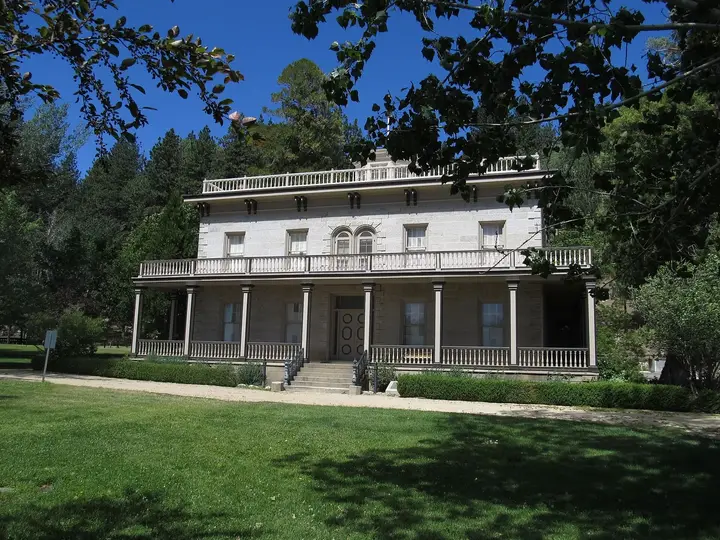 Front of the historic two story Bowers Mansion with wide verandas behind a green lawn
