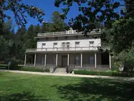 Front of the historic two story Bowers Mansion with wide verandas behind a green lawn